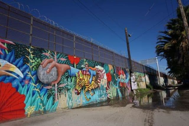 Képeket fest az Egyesült Államok és Mexikó közötti falra egy mexikói művész